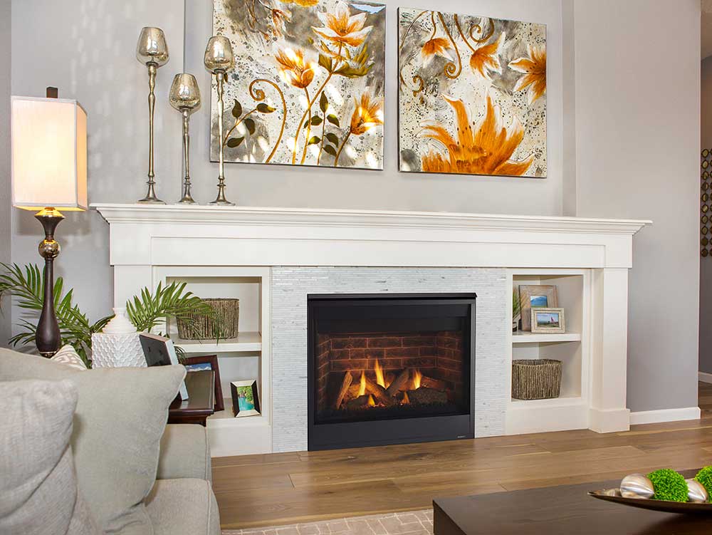 Majestic Quartz gas fireplace with brick interior and black surround flanked by bookcases under mantel in living room with botanical paintings above fireplace