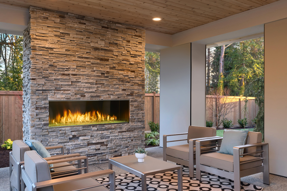 Outdoor Lifestyles Lanai 60 linear gas fireplace by Majestic shown in a covered patio with yellow LED lights on