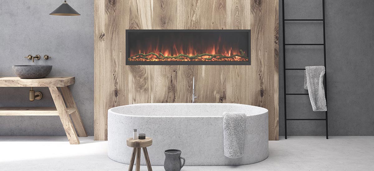 Lanscape Pro Slim electric fireplace with orange flames in wood wall behind stone bath tub in room with grey walls and light gray floor.