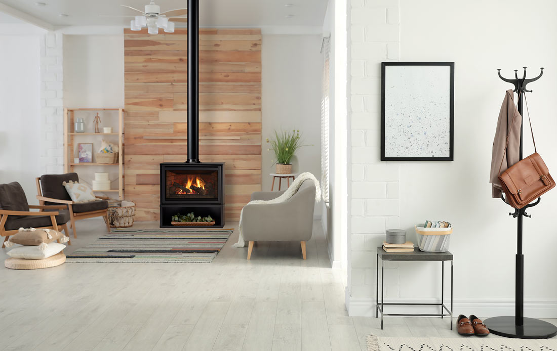 Majestic Trilliant freestanding gas fireplace in white living room backed by wood plank wall