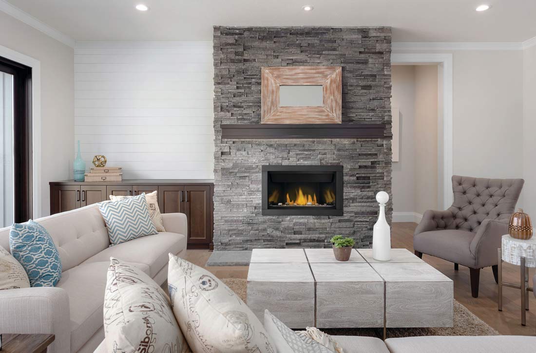 Gas fireplace surrounded by gray stone tile in living room with white sofa, marble block coffee table, and taupe side chair.