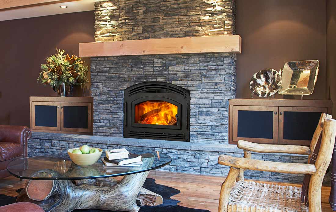 Majestic Pioneer 2 wood burning fireplace with arched door surrounded by grey stone, brown walls, rustic cabin furniture