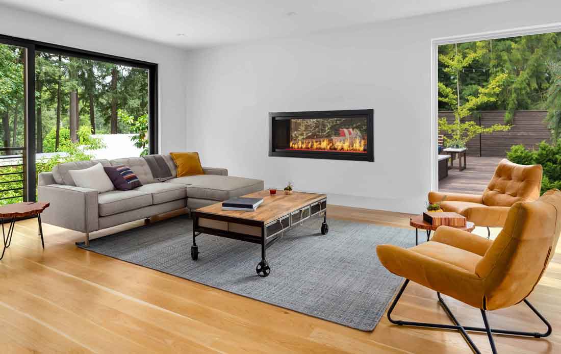 Monessen Artisan see-through linear vent free gas fireplace on a white exterior wall with black contemporary front, gray sofa, industrial table, orange chairs