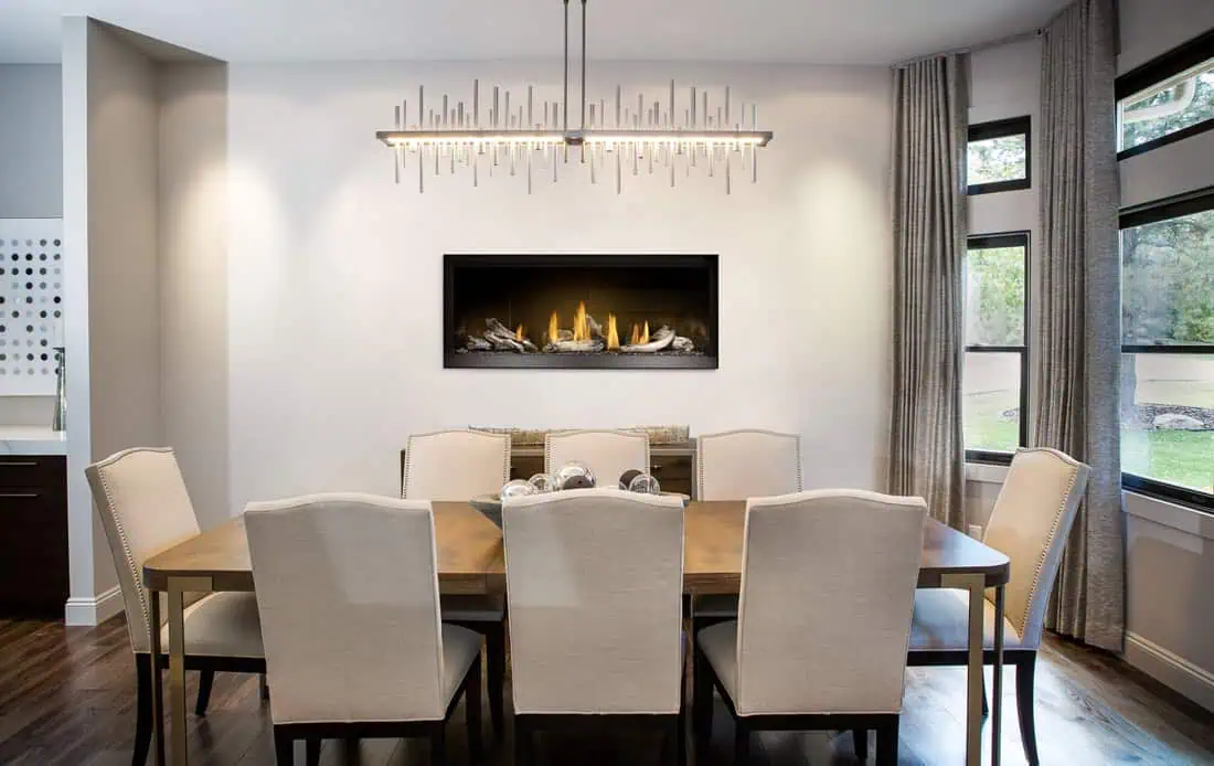 Napoleon Ascent Linear Premium 46-inch gas fireplace on white wall behind wood dining table surrounded by eight white upholstered chairs
