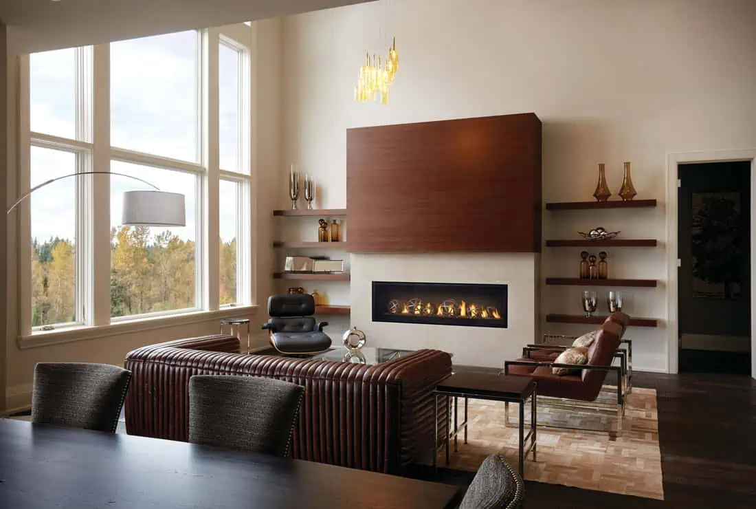 Napoleon Luxuria 62 linear gas fireplace in great room with vaulted ceiling, wall of windows to left, brown sofa and chairs, black chair, glass table