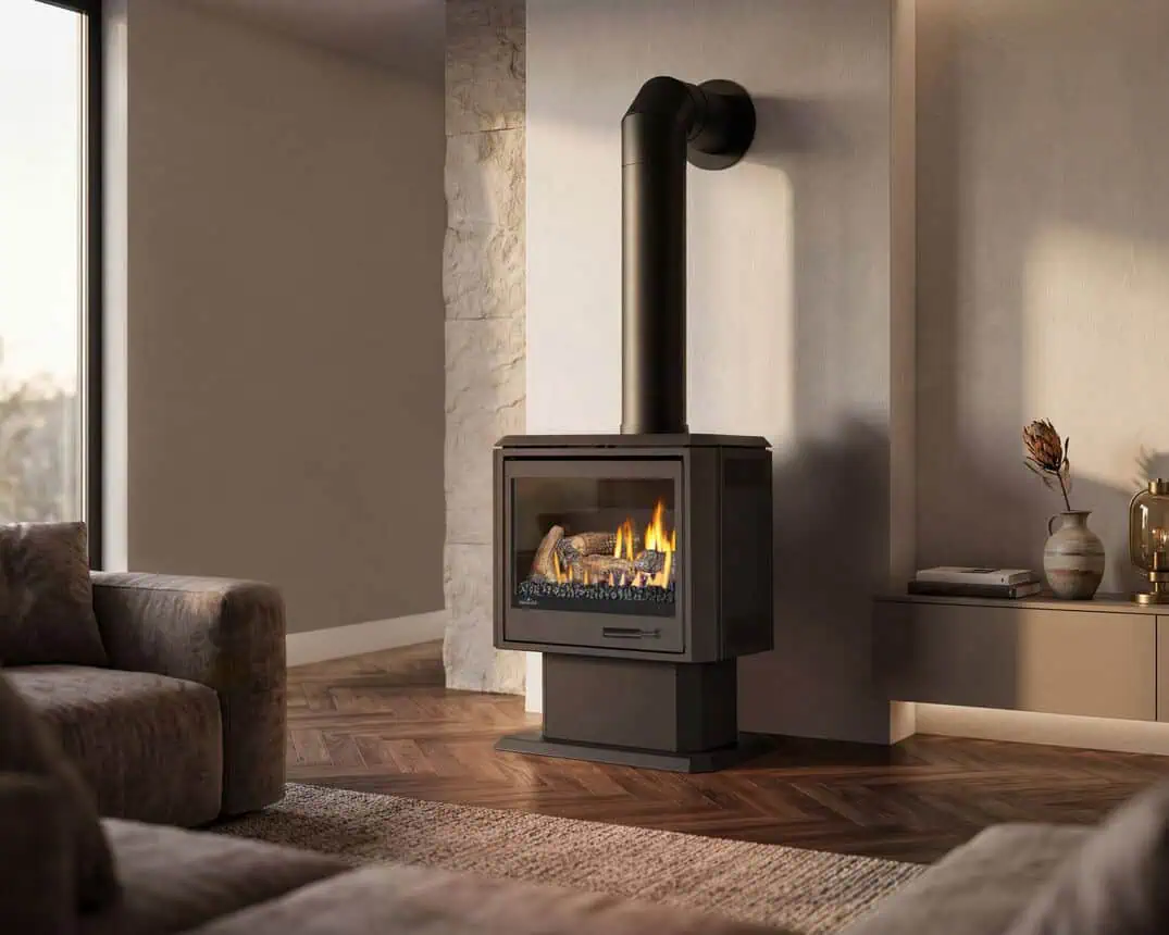 Napoleon Havelock Elite gas stove on a pedestal base in a warm neutral tone living room with plastered and stone walls, parquet wood floor, large window to left.